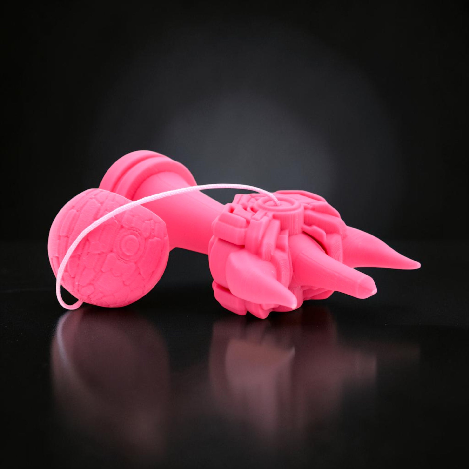 Kendama Geeker Iron S roz, din plastic, cu un design inspirat de armură, pe fundal negru.