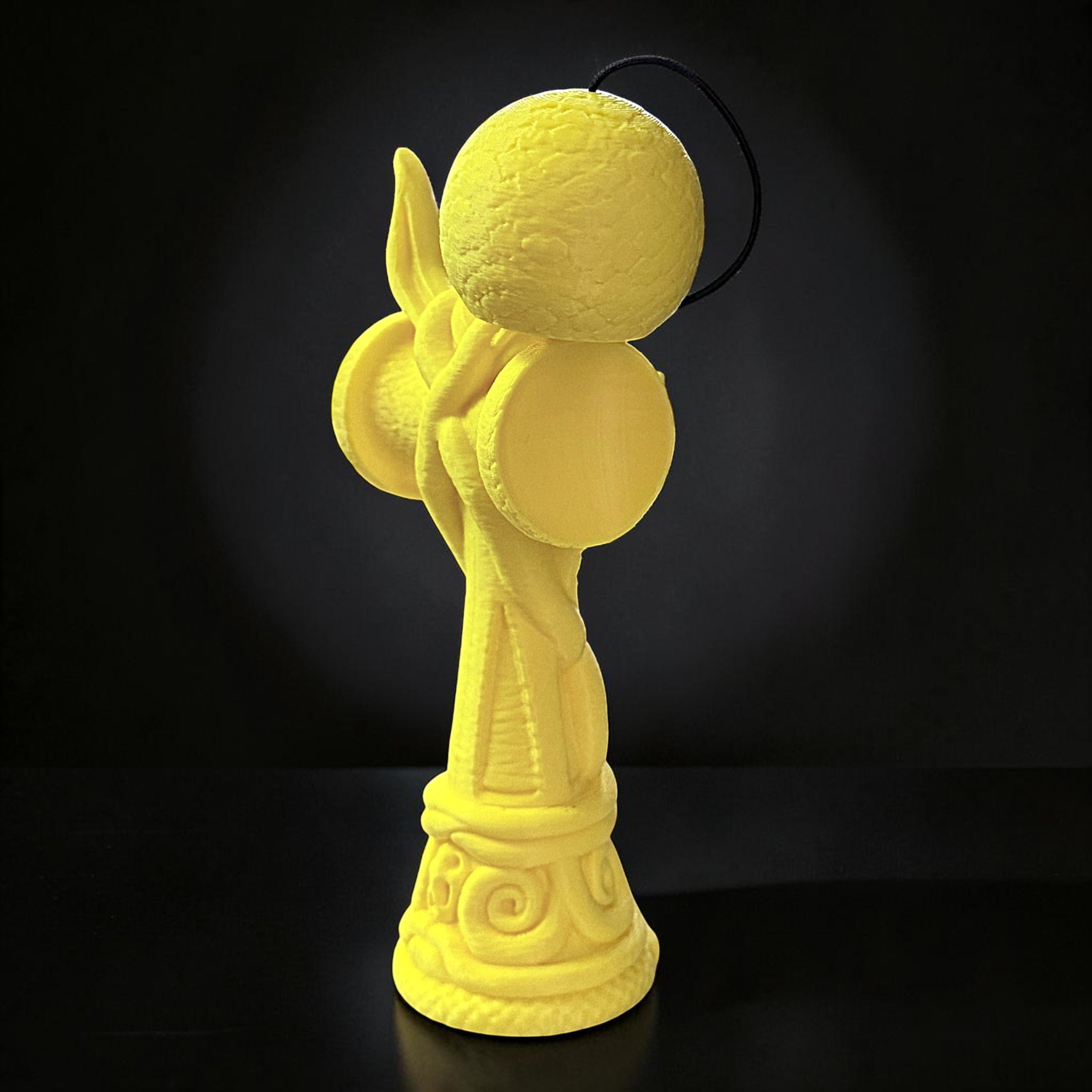 Jucărie Kendama Cobra Tom GO din lemn de fag, galben, cu design detaliat de șarpe încolăcit, ideală pentru trick-uri complexe.