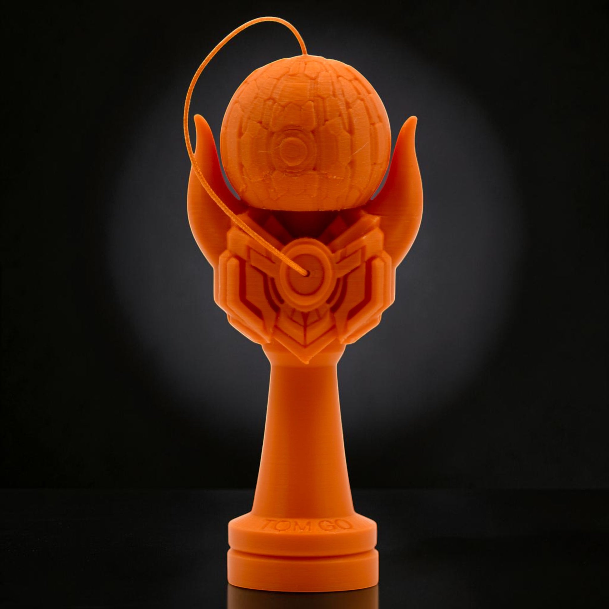 Tom GO Kendama Geeker Iron M, orange, with intricate design on the tama and a stylized base.