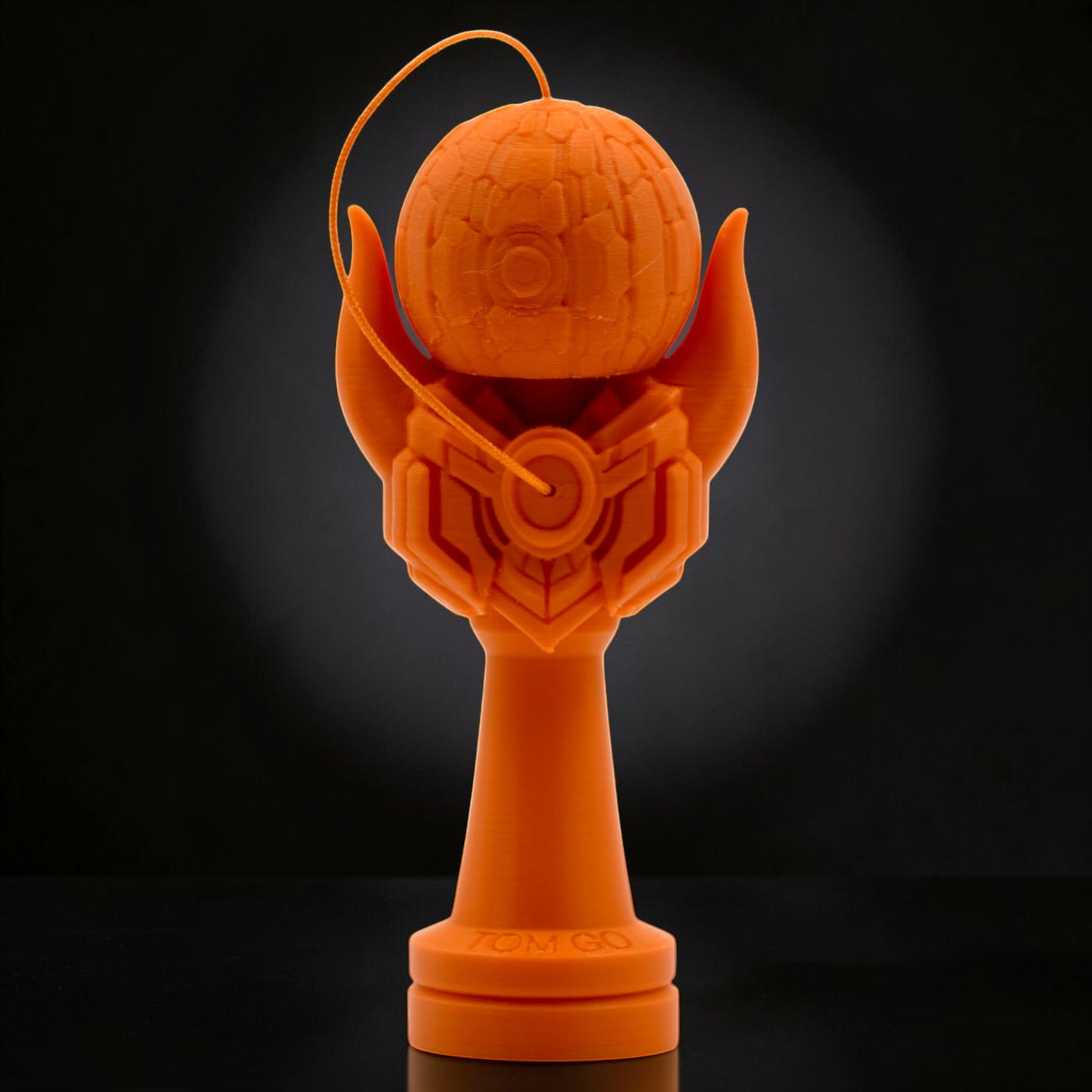 Tom GO Kendama Geeker Iron M, orange, with intricate design on the tama and a stylized base.