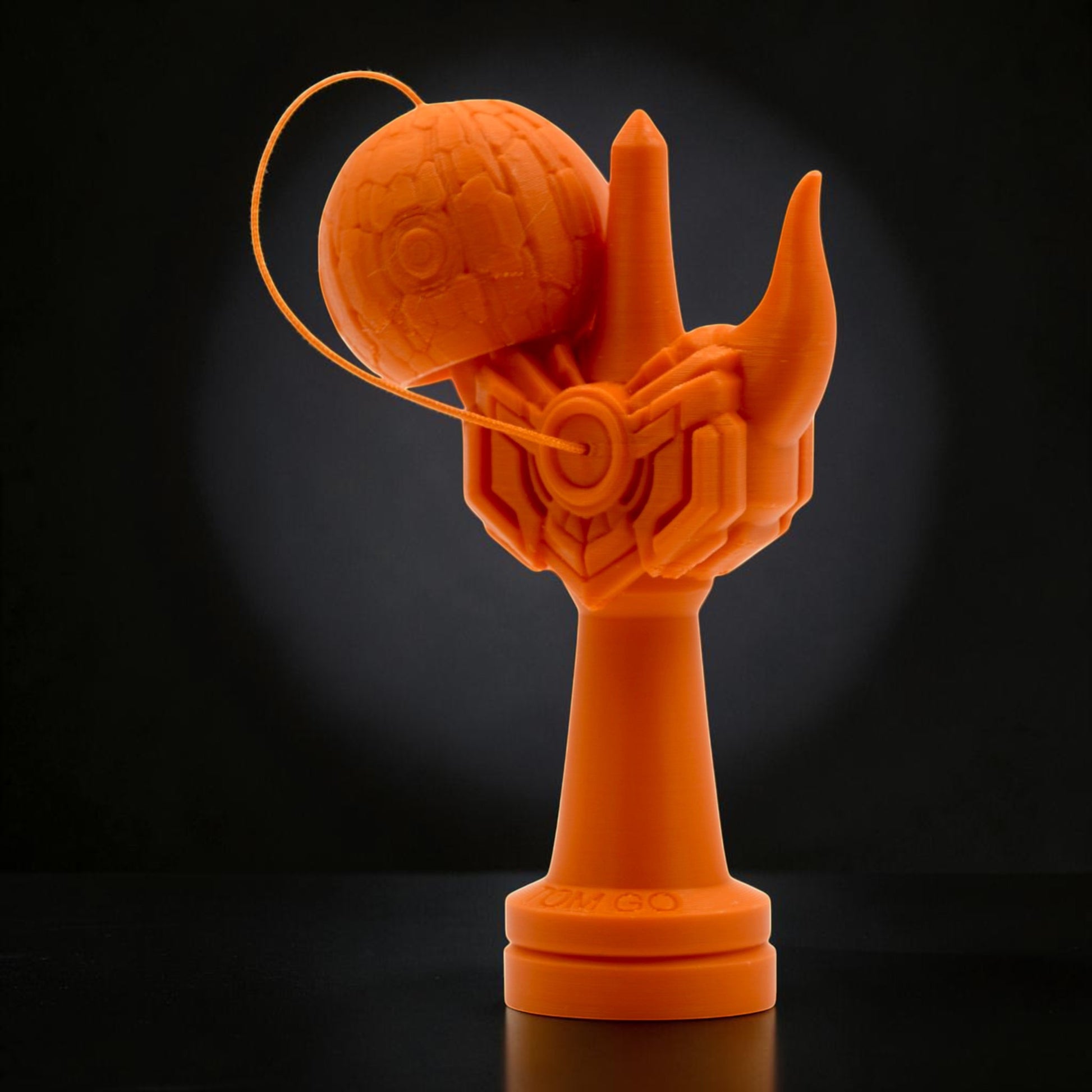 Tom GO Kendama Geeker Iron M, orange, with intricate hand design and textured tama.