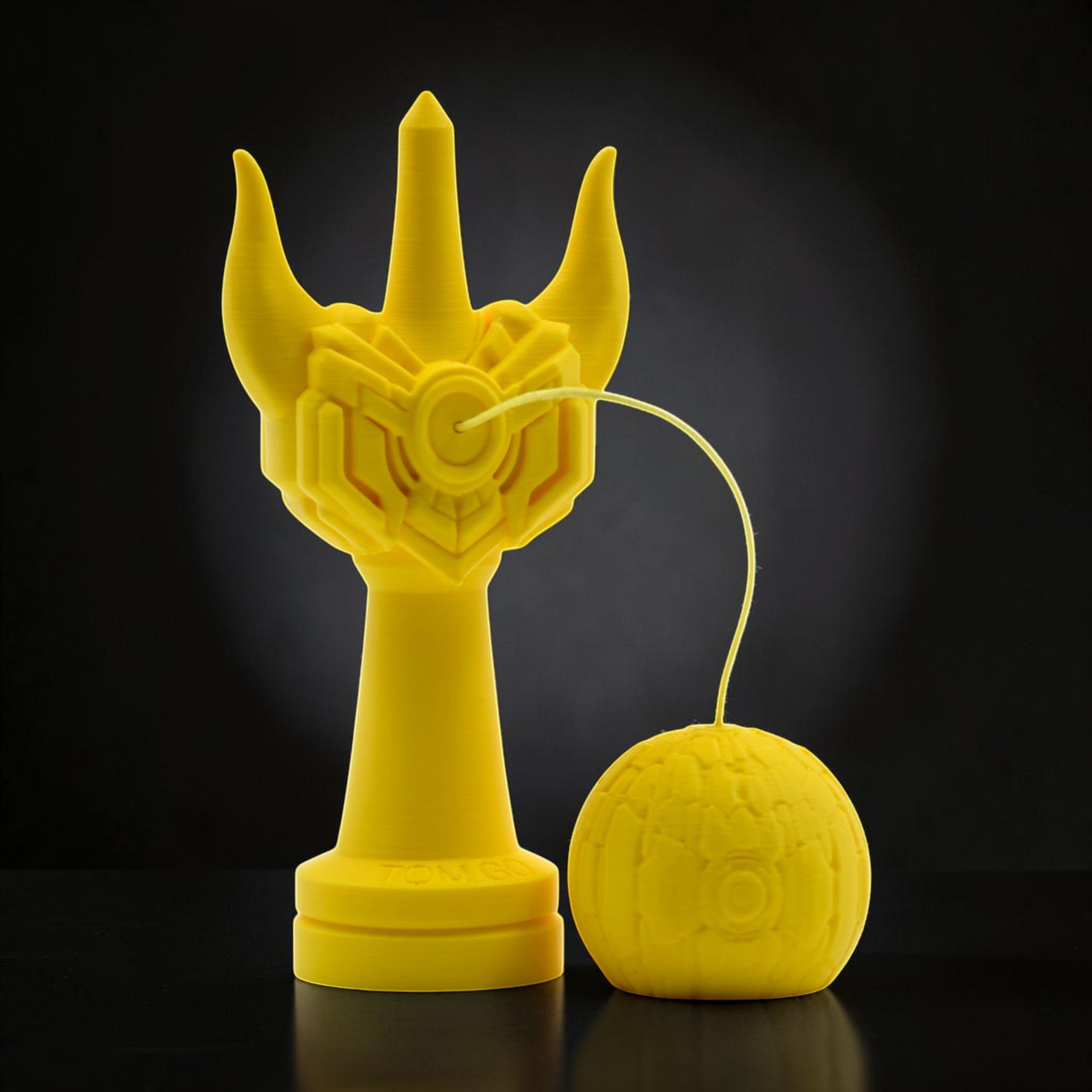 Tom Go Kendama Geeker Iron M, a bright yellow kendama with a unique, armor-inspired design on the cup and a textured tama.