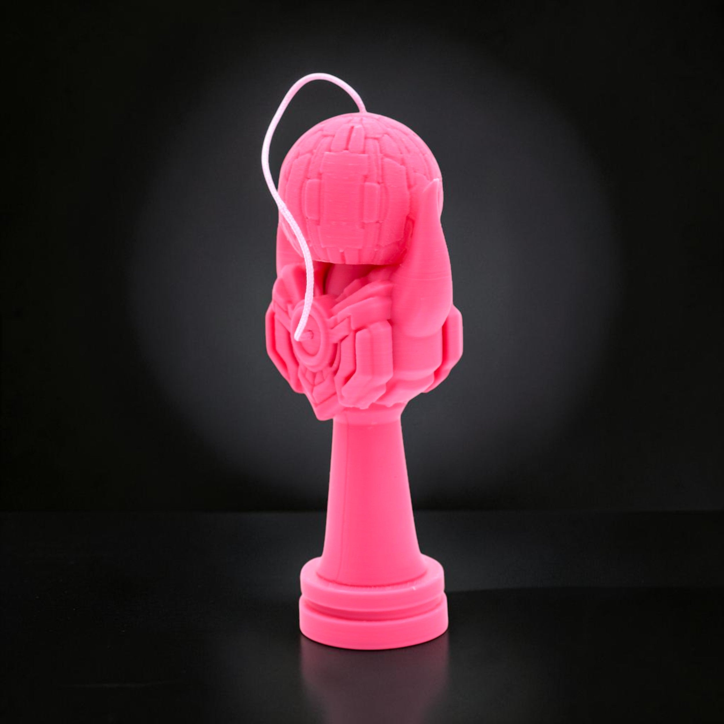 Kendama Geeker Iron S roz, din plastic, cu un design futurist, pe un fundal negru.