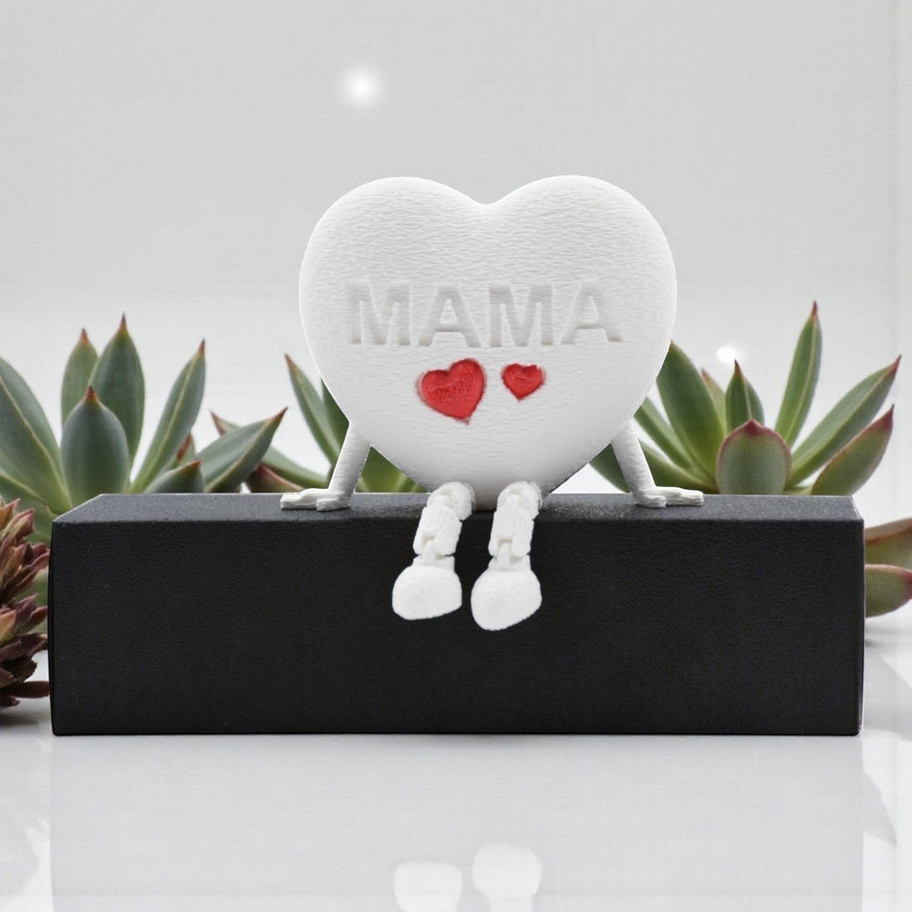 Tom GO white heart figurine with articulated legs, embossed with MAMA and two red hearts. Decorative accent.