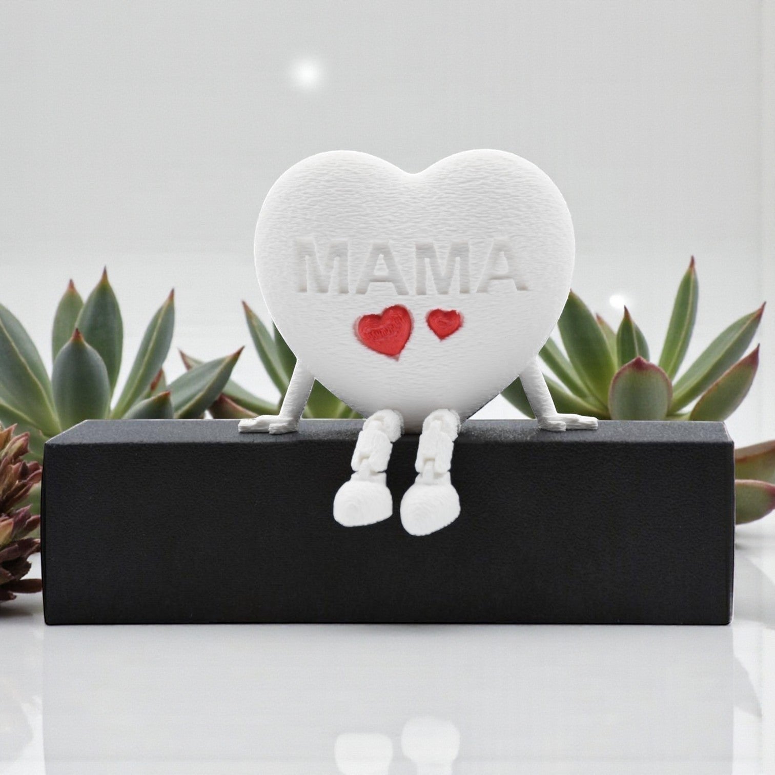 Tom GO white heart figurine with articulated legs, embossed with MAMA and two red hearts. Decorative accent.