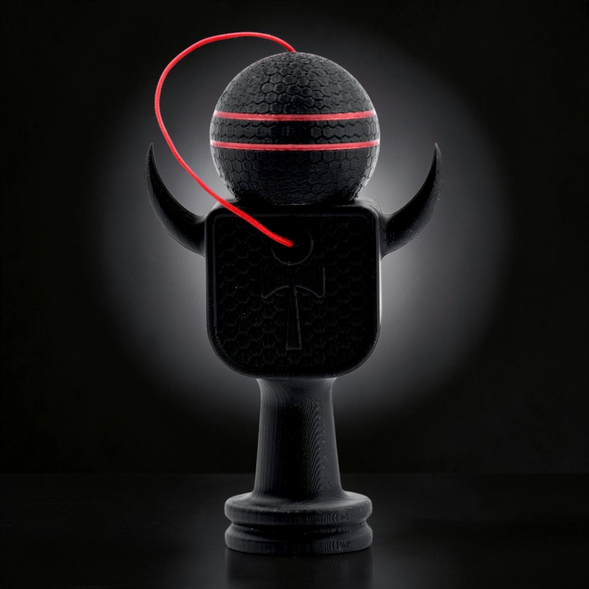 Kendama Geeker XLine M neagră, cu șnur roșu și dungi roșii pe bilă, din plastic rezistent.