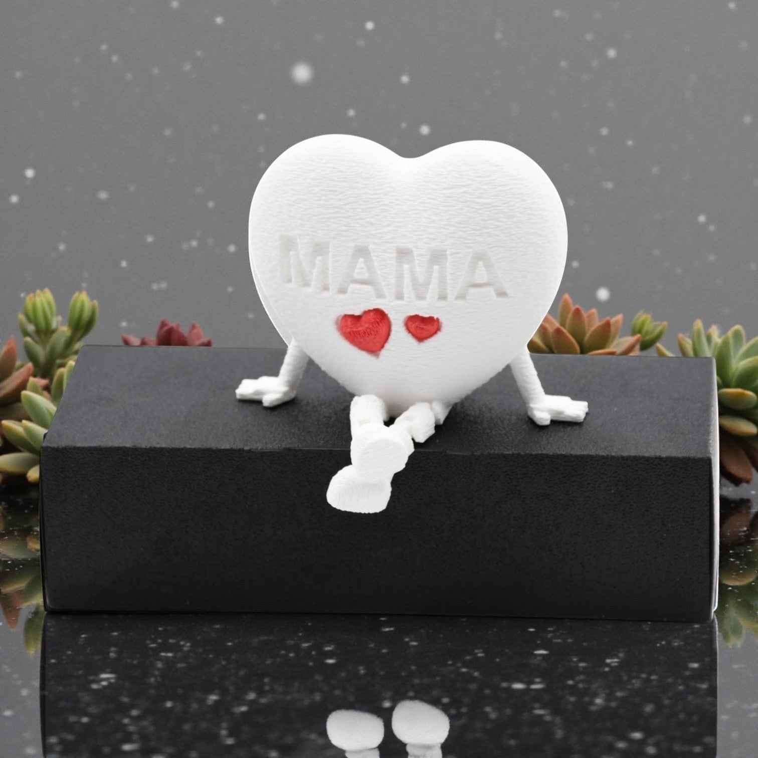 Tom Goh white heart figurine with articulated legs, embossed with MAMA and two red hearts. Decorative accent.