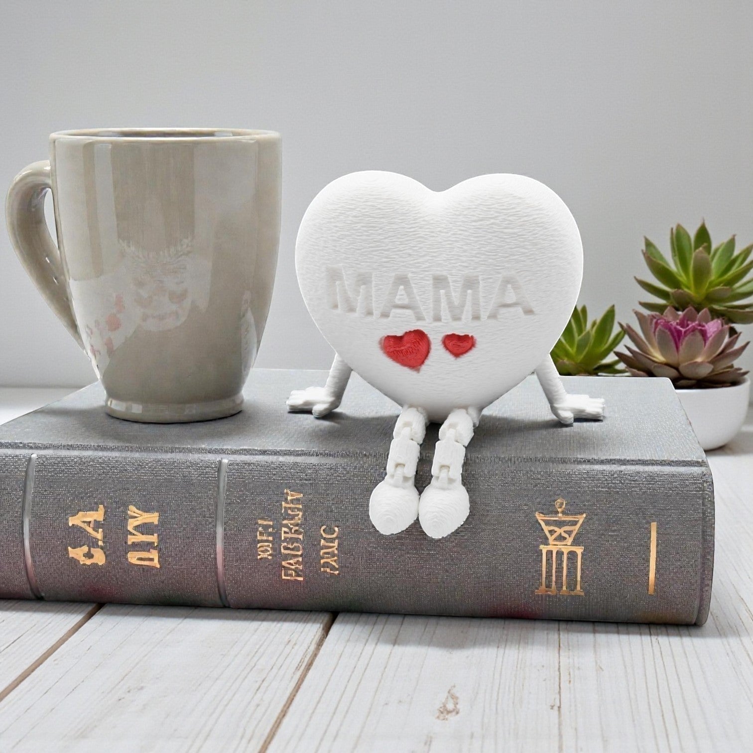 Tom GOHere white textured heart figurine with articulated legs, embossed with "MAMA" and two red hearts.